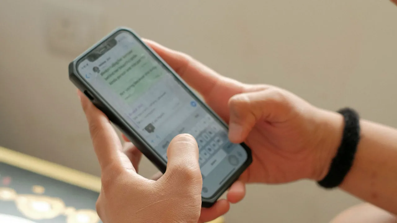 Hände halten ein Smartphone, auf dem WhatsApp geöffnet ist